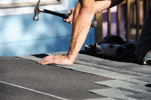 Person installing new roofing shingles
